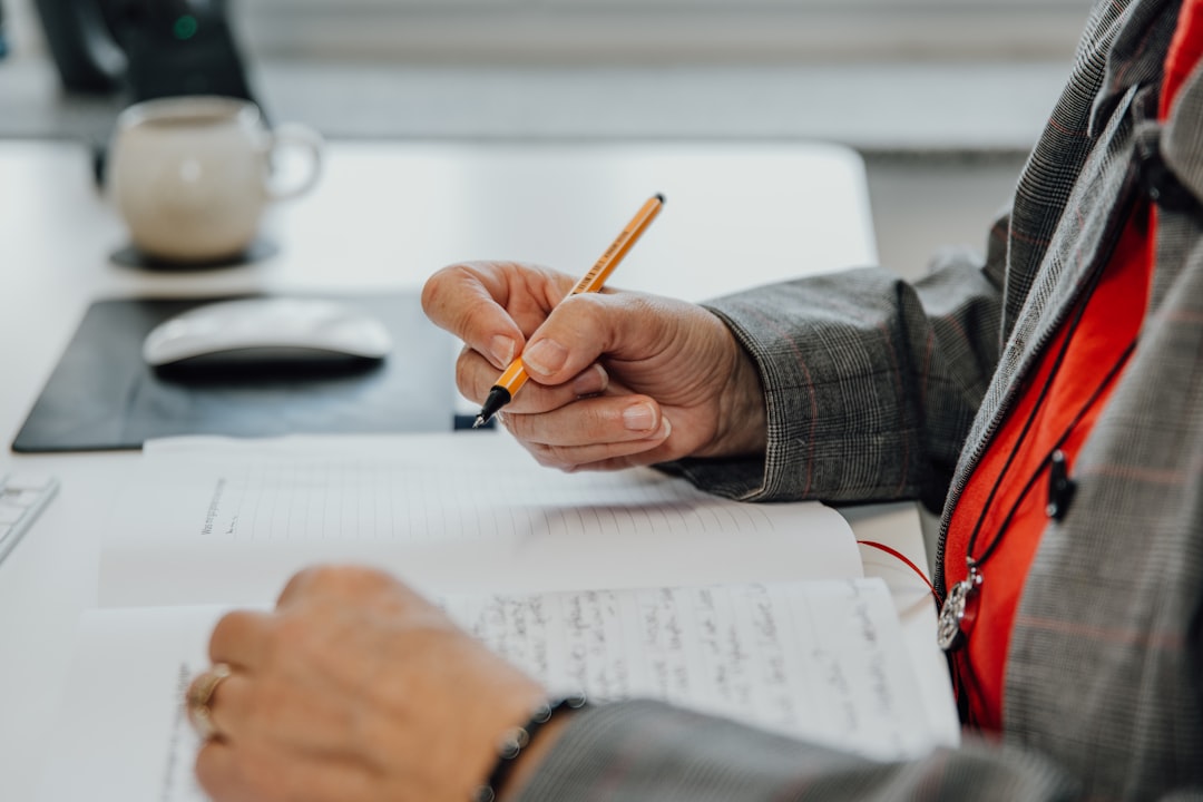 a-person-sitting-at-a-desk-writing-on-a-piece-of-paper-7vc-j-otnm8